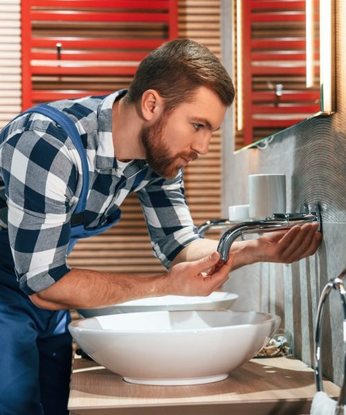 plumber-in-blue-uniform-is-at-work-in-the-bathroom-e1686029515618